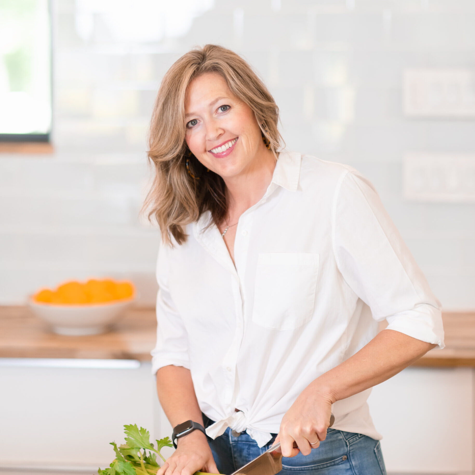 Lifestyle branding photo of a woman preparing fresh vegetables in a light-filled kitchen.
